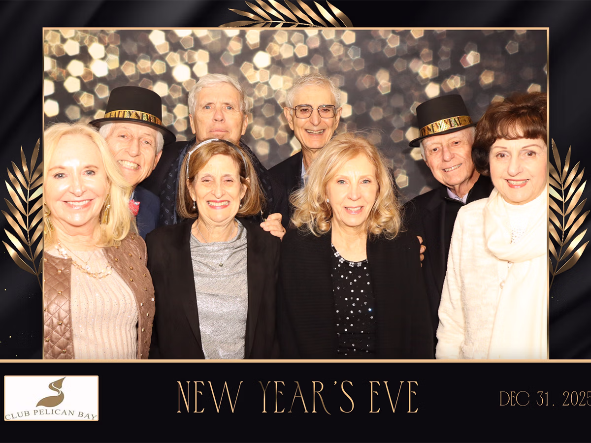 A group of couples smiling in a custom frame and backdrop at a country club event