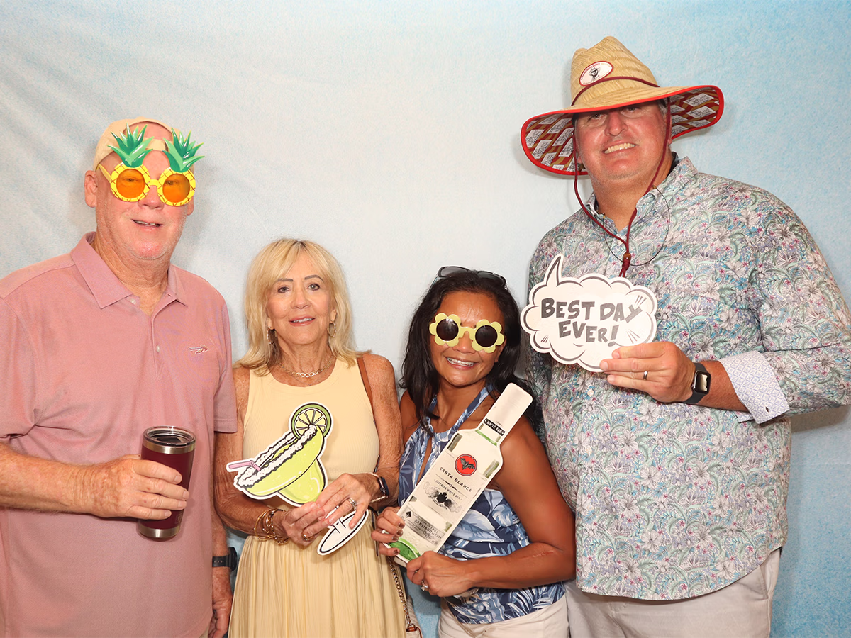 Two couples smiling with props at a country club event