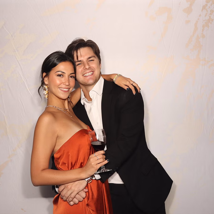 A couple smiling in a Photo Booth at a wedding on a gold marble background