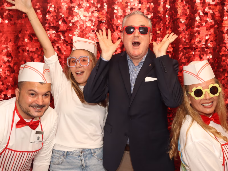 a group of four posing and smiling in a photo booth rental by photo magic events