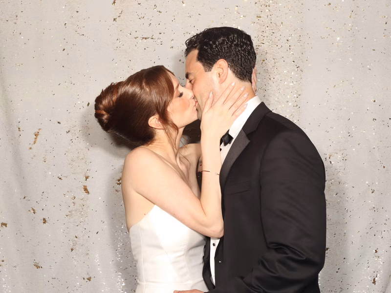 Newlyweds kissing in their wedding photo booth rental from Photo Magic Events