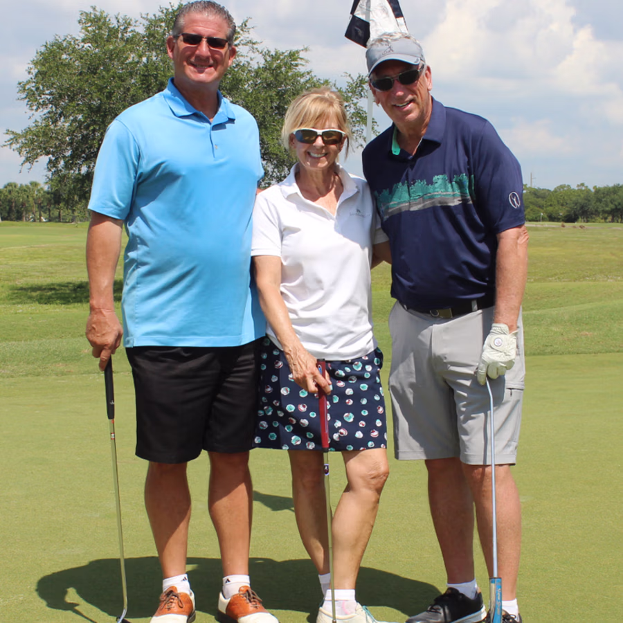 A group of golfers smiling in front of a putting green in a Roaming Photo Booth