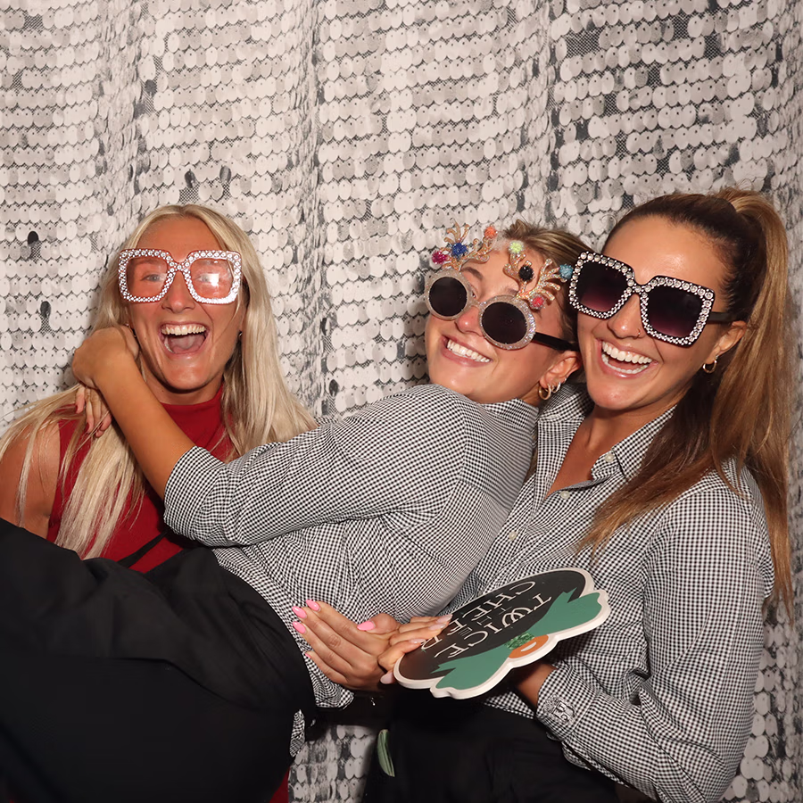 A group of girls smiling and laughing with props in a Photo Booth
