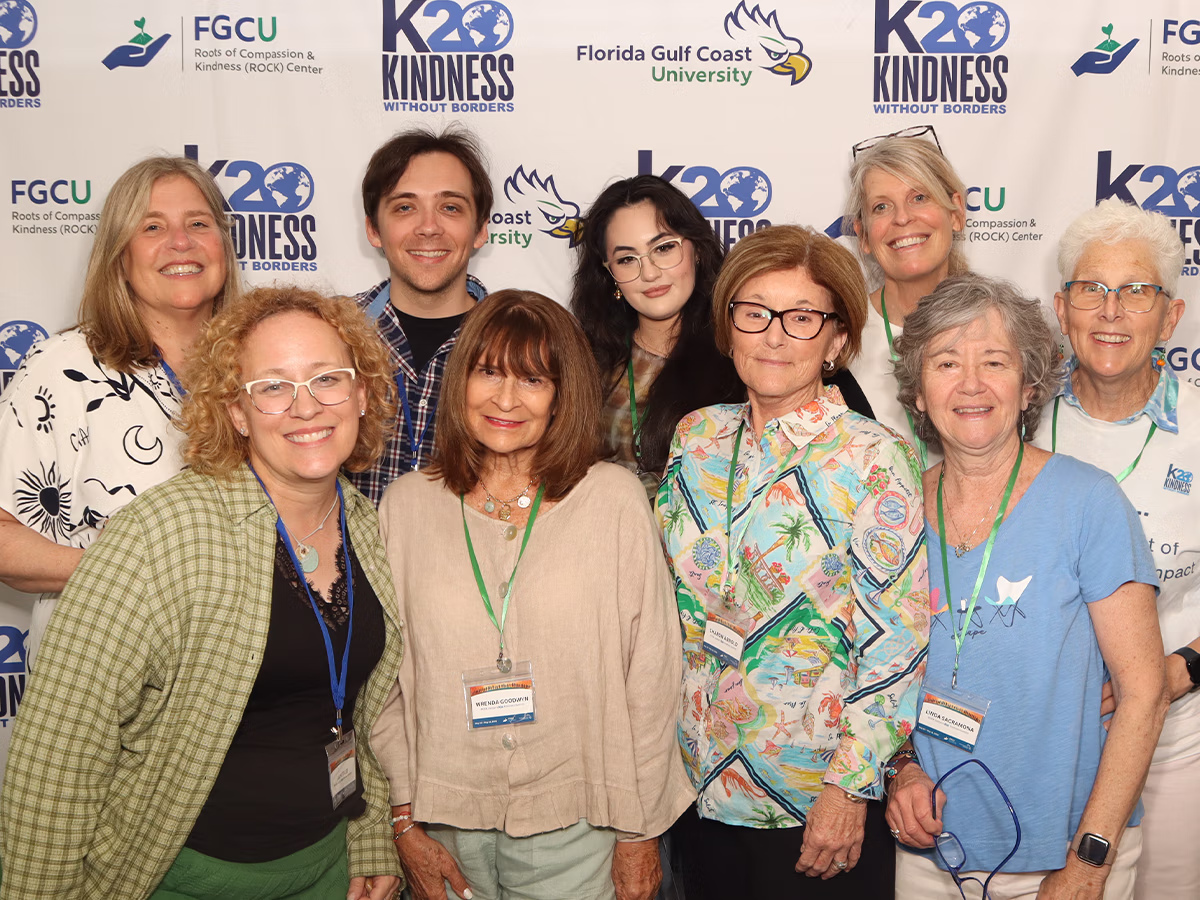 Group of attendees in front of a step and repeat for an FGCU corporate event